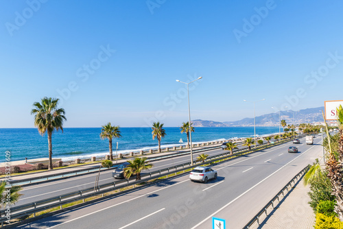 Highway Road with Cars Moving Next to a Blue Sea and Sandy Beach Under The Clear Sky in a Hot Sunny Summer day from a Pedestrian Stone Bridge © mohammad