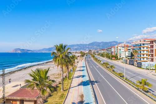 Fototapeta Naklejka Na Ścianę i Meble -  Empty Highway Road Next to a Blue Sea and Sandy Beach Under The Clear Sky in a Hot Sunny Summer day from a Pedestrian Stone Bridge