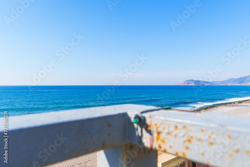 Clear Blue Sea and Sandy Beach from a Pedestrian Bridge Crosswalk Under the Clear Sky in a Sunny Bright Day