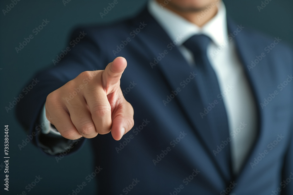 A male businessman in a business suit points his finger in the direction on a grey background A male businessman in a business suit points his finger in the direction on a grey background