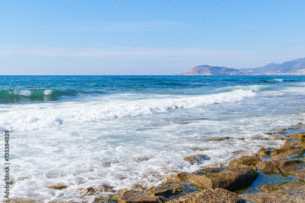 Majestic Calm Blue Ocean Waves Hitting and Splashing on the Seashore and Beach Under the Clear Sky, During a Hot Sunny Summer Day Morning 