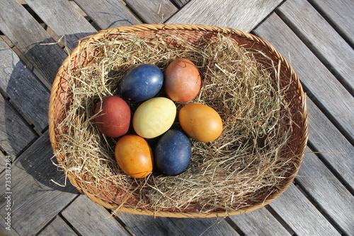 Naturally colored Easter eggs in a basket on a meadow