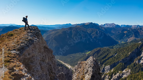 Hiker man standing on mountain summit with panoramic view of majestic Hochschwab massif, Styria, Austria. Idyllic hiking trail in remote Austrian Alps. Sense of escapism, peace, personal reflection