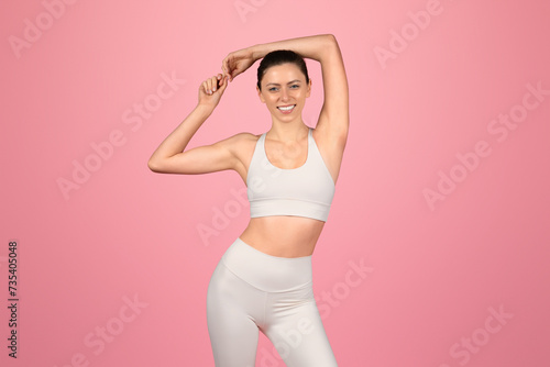 Confident and fit, a woman in a white sports bra and leggings stretches her arms