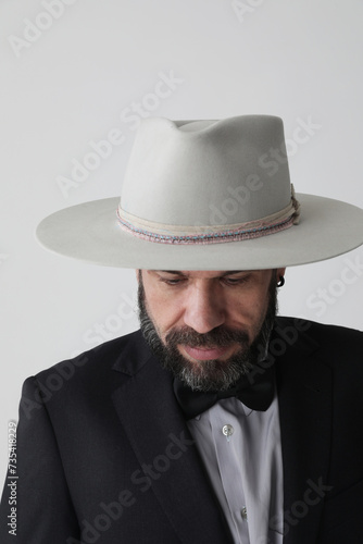 Vertical portrait of man wearing hat looking away and poses at the studio. 