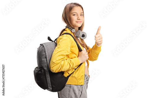 Female teen student with headphones and backpack gesturing thumbs up