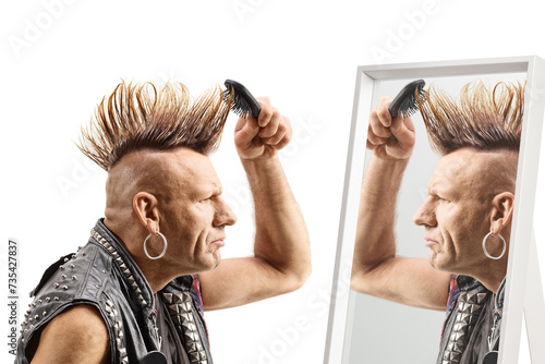 Man combing his mohawk hairstyle with a brush in front of a mirror photo