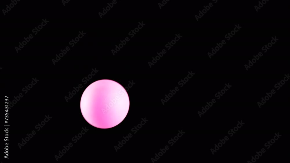 Pink Small Tennis Ball Spinning in Copy Space on Black Background. Abstract. Side view. Plastic sphere or ball balances in the air flow. levitation. Selective focus. One hovering, flying ball. Light. Pink Small Tennis Ball Spinning in Copy Space on Black Background. Abstract. Side view. Plastic sphere or ball balances in the air flow. levitation. Selective focus. One hovering, flying ball. Light.