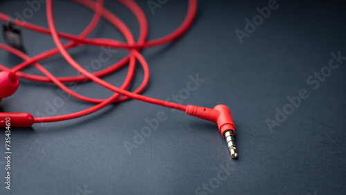 Red earphones are elegantly displayed against a sleek black background, with ample space available for text. The bold red color of the earphones contrasts beautifully with the dark backdrop, creating 