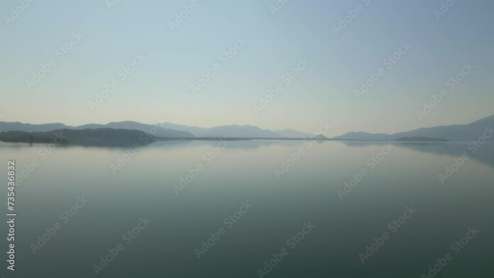 A serene natural landscape with a lake reflecting the sky, surrounded by misty mountains in the background. A serene natural landscape with a lake reflecting the sky, surrounded by misty mountains in the background.
