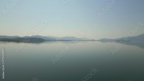 Wallpaper Mural A serene natural landscape with a lake reflecting the sky, surrounded by misty mountains in the background. Torontodigital.ca