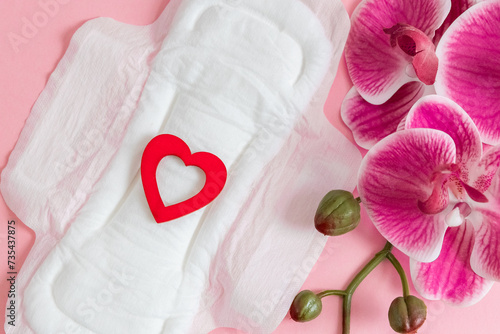 Women's sanitary pad with red heart and orchid on a pink background. photo
