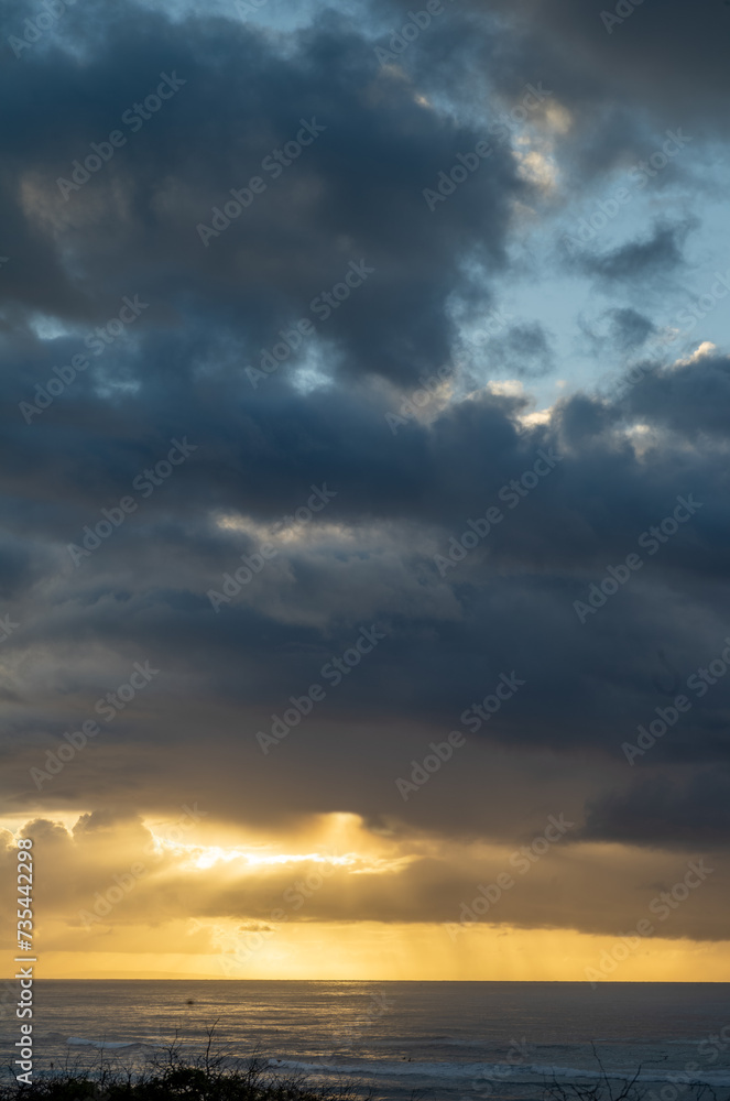 Sunset View of Diamond Head Beach with Gold and Gray Clouds and Sunlight in a Rain Shower. Sunset View of Diamond Head Beach with Gold and Gray Clouds and Sunlight in a Rain Shower.