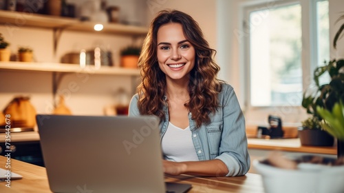Smiling young woman using a laptop in her kitchen.