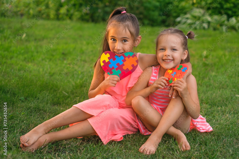 Children show their heart-shaped postcards decorated with colored puzzles - a symbol of autism Children show their heart-shaped postcards decorated with colored puzzles - a symbol of autism