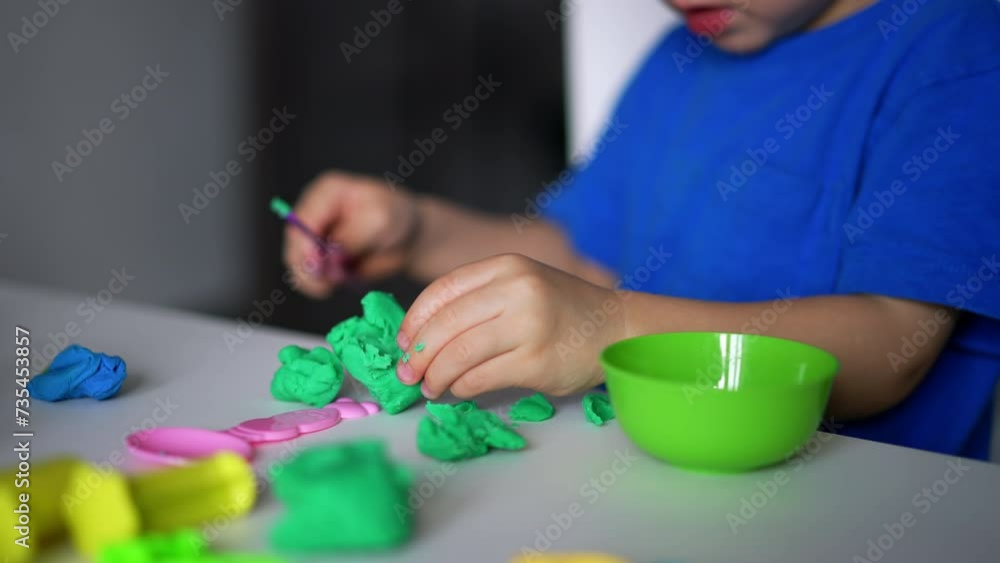 Unrecognized toddler using a stick to cut the plasticine into pieces. Little child playing at home. Close up. Unrecognized toddler using a stick to cut the plasticine into pieces. Little child playing at home. Close up.