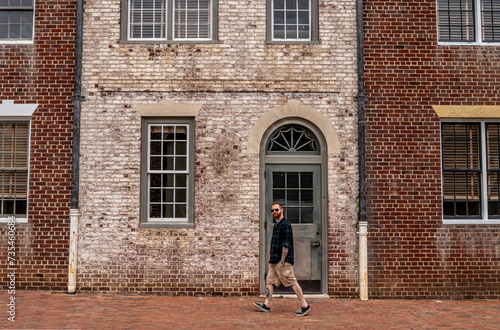 Stylish Man Walking Down a Street in Front of a Dual Colored Brick Facade in Historic Williamsburg Virginia