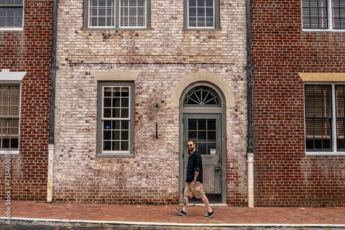 Stylish Man Walking Down a Street in Front of a Dual Colored Brick Facade in Historic Williamsburg Virginia