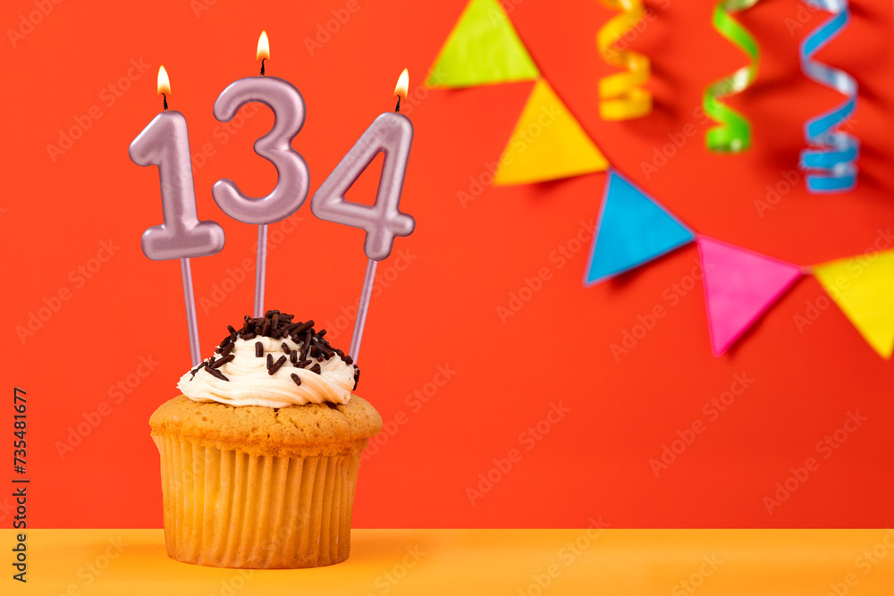 Birthday cupcake with number 134 candle - Sparkling orange background with bunting