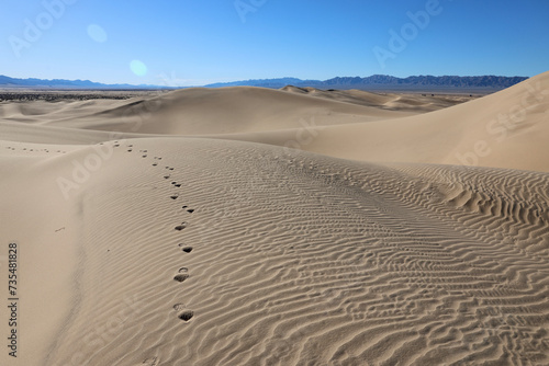footprints across the sand dunes in the desert