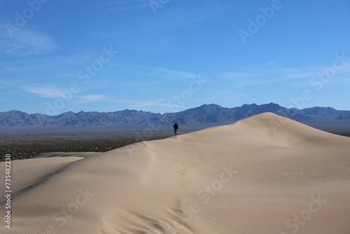 Lone hiker explores the desert sand dunes