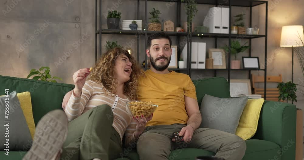 Couple caucasian man and woman sit at home on sofa bed watch tv movie Couple caucasian man and woman sit at home on sofa bed watch tv movie