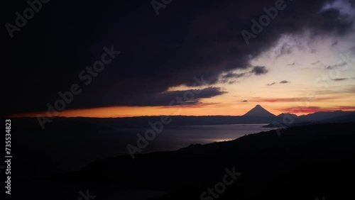 Time lapse of cloudy sunrise over Arenal volcano in central Costa Rica with nearby lake on the foreground photo