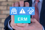 Businessman holding multi-colored styrofoam blocks sees abbreviation: ERM. Enterprise Risk Management ( ERM ) Forecasting Evaluation Financial Business concept.