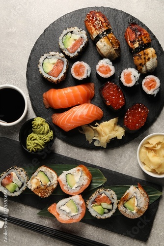 Different tasty sushi rolls on light grey table, flat lay