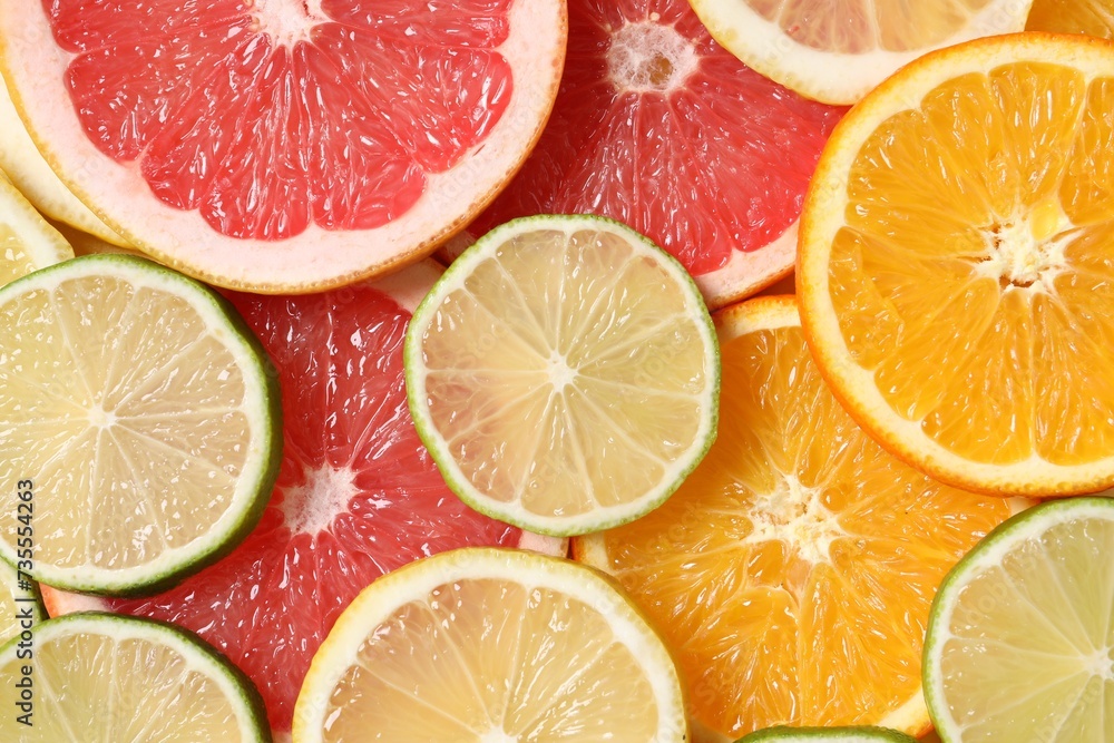 Different sliced citrus fruits as background, top view