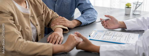 Photos Doctor providing compassionate healthcare consultation while young couple patient holding hand, comfort each other after infertile report