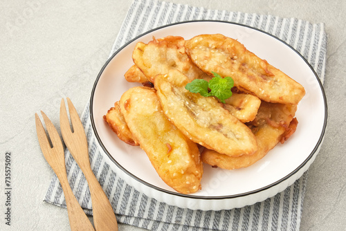 Pisang Goreng Wijen or banana fritters with sesame seed served in white plate. Indonesian food
