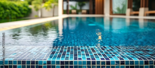 Tranquil blue tile pattern pool surrounded by lush greenery and illuminating natural sunlight photo