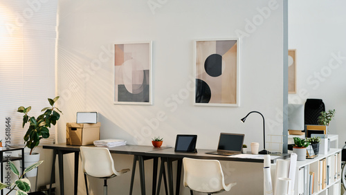 No people shot of interior of workspace in modern office equipped with minimalistic furniture and decorated with abstract paintings, copy space photo
