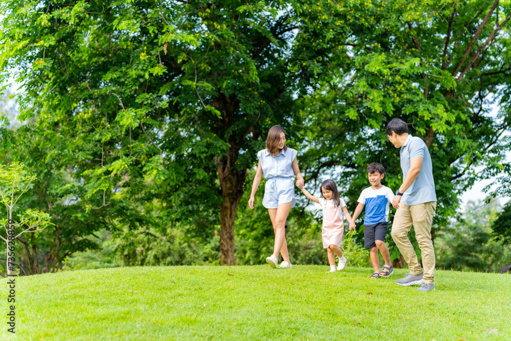 Happy Asian family enjoy and fun outdoor lifestyle on summer holiday vacation. Parents and little child daughter and son spending time exercising and playing together at public park in the city.