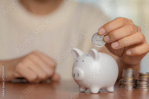 Woman hand putting coin into piggy bank for savings, finance, and wealth in a business and banking concept