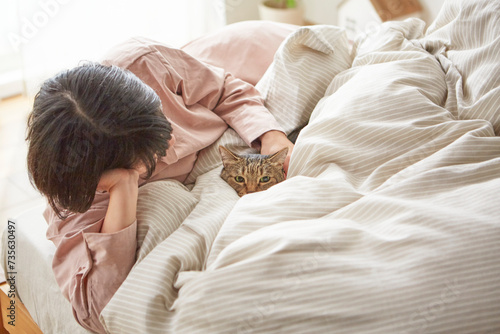 ベッドのうえで猫と戯れる女性 photo