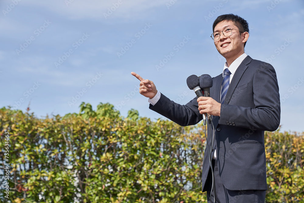 マイクを持っているスーツを着た男性