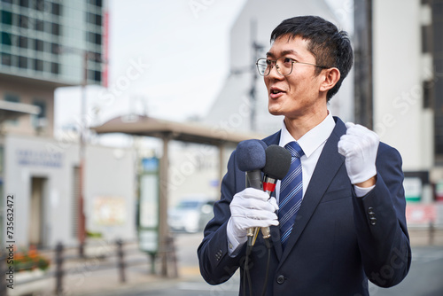 街中で演説をするスーツを着た男性 photo