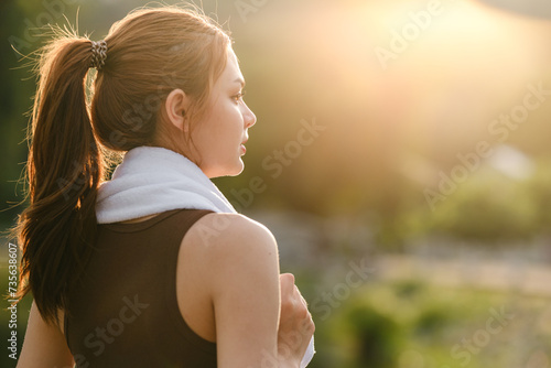 Happy slim woman wearing sportswear in the garden at sunrise. Young beautiful asian female in sports bra running outdoor. Workout exercise in the morning. Healthy and active lifestyle concept. photo
