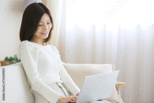ソファーでパソコンを操作する女性 photo