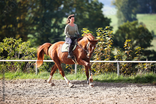 Horse woman rider riding in the sunshine at the riding arena.