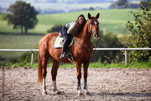 Horse woman rider riding in the sunshine at the riding arena.