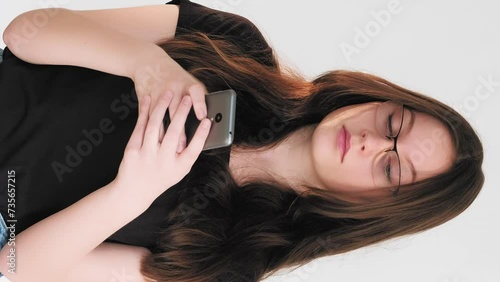 Vertical video. Mobile conflict. Angry chat. Annoyed dissatisfied woman arguing texting message using phone app isolated on white. photo