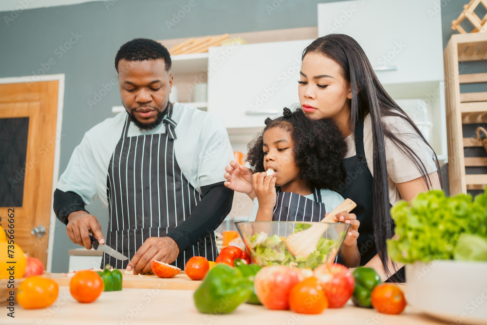 Kind African american parents teaching their adorable daughter how to cook healthy food, free space of kitchen, Happy black people family preparing healthy food in kitchen together Kind African american parents teaching their adorable daughter how to cook healthy food, free space of kitchen, Happy black people family preparing healthy food in kitchen together