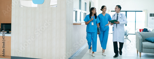 Φωτογραφία Mature female doctor discussing medical report with nurses in hospital hallway
