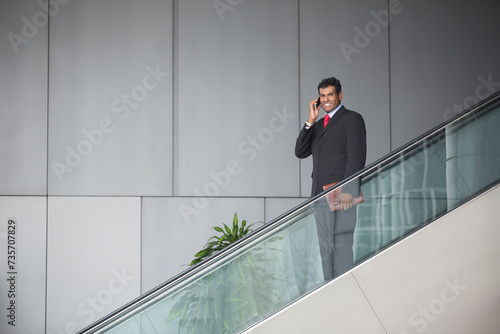 Indian businessman standing on an escalator.