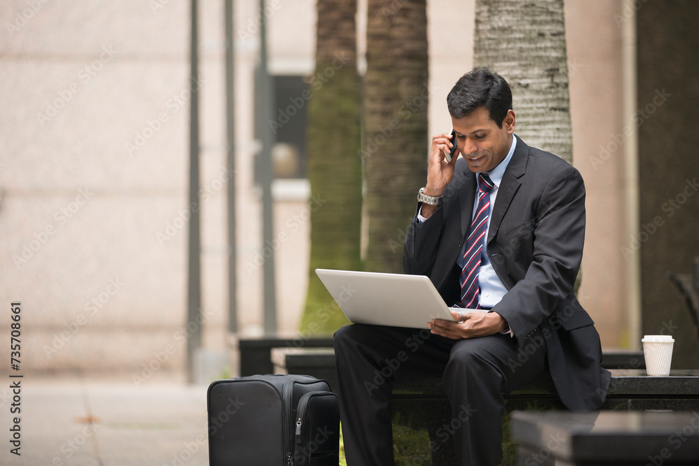 Indian businessman using his laptop outdoors. Indian businessman using his laptop outdoors.