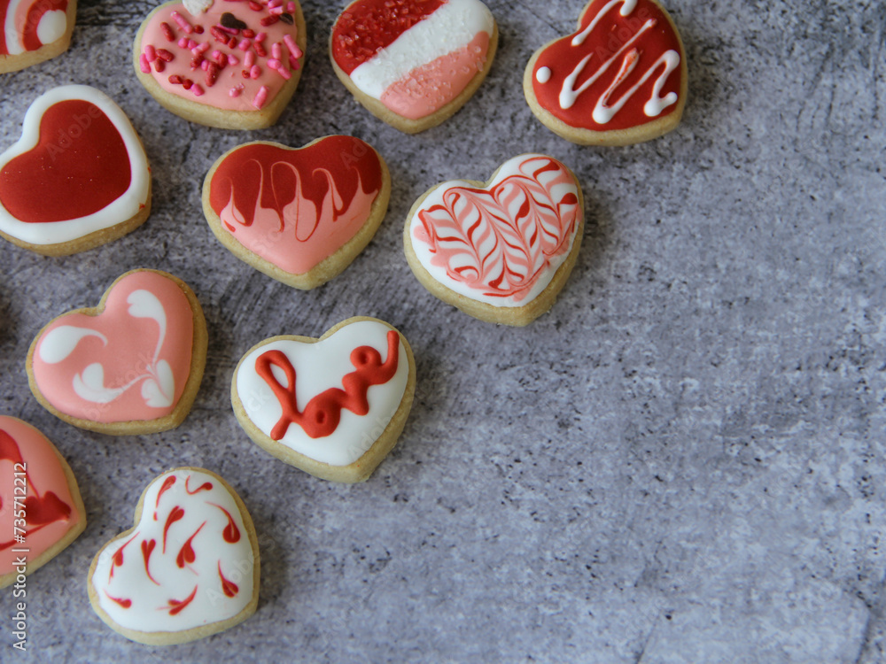 Heart shaped homemade cookies flat lay decorated with textured red and white icing designs for Valentine's Day on gray background with copy space, suitable for background, wallpaper or screensaver. Heart shaped homemade cookies flat lay decorated with textured red and white icing designs for Valentine's Day on gray background with copy space, suitable for background, wallpaper or screensaver.