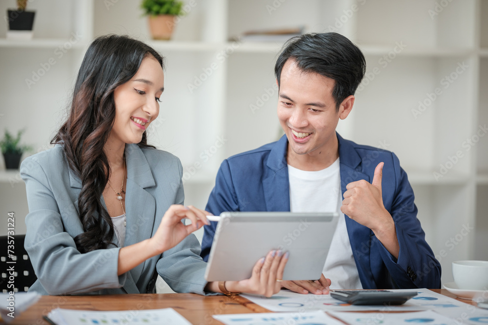 Two business workers smiling happy working sitting on desk at the office. Two business workers smiling happy working sitting on desk at the office.